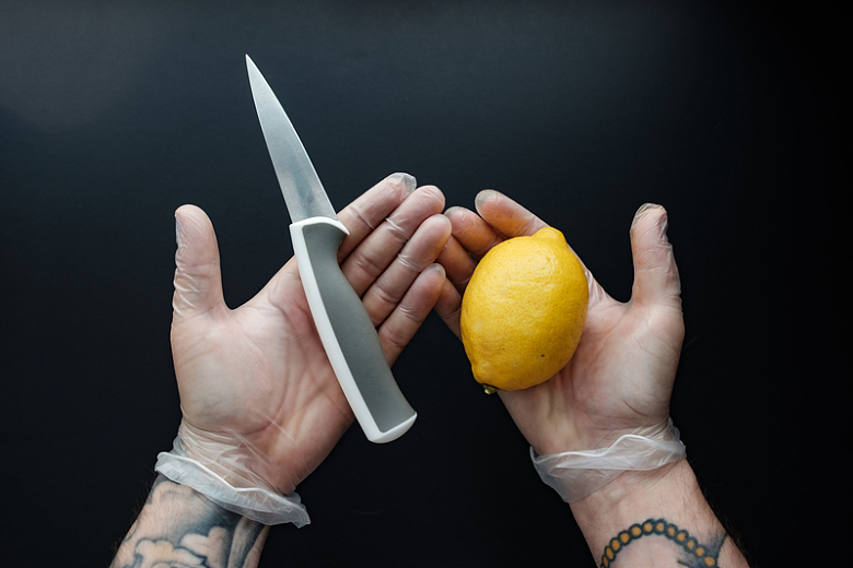 戴着手套的手拿着刀和柠檬