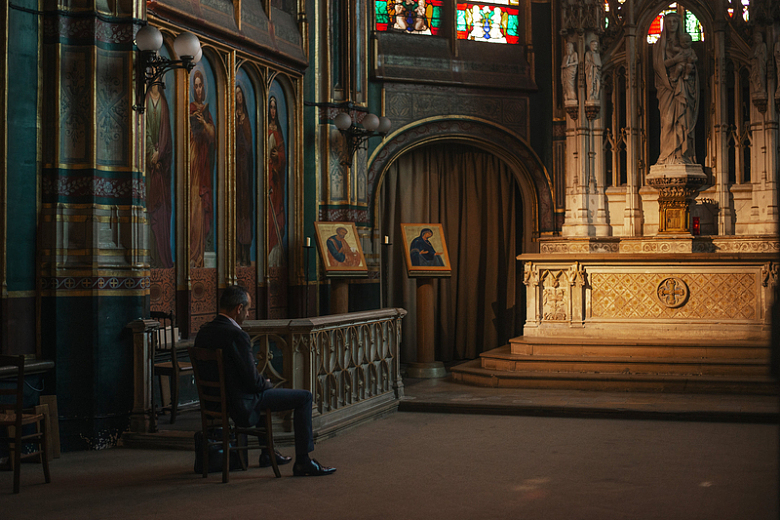 巴洛克风格教堂里一个穿着西装的男子坐在椅子上