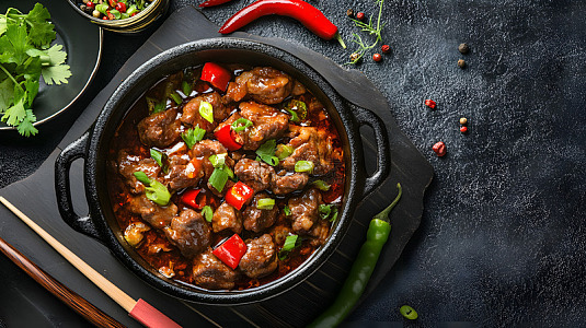 黑色砂锅中辣味炖牛肉美食摄影图
