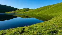 翠绿山坡映衬清澈湖水的宁静自然风光