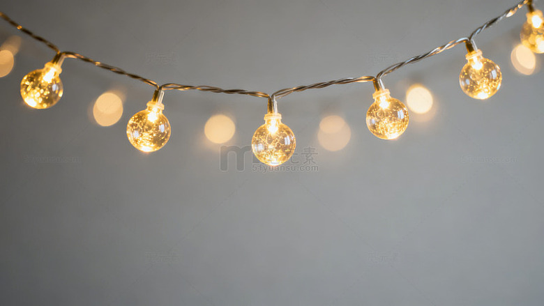 一串暖黄色灯泡悬挂于灰色背景前