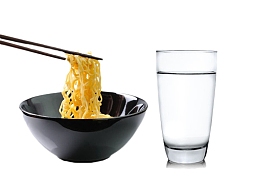 夹着黑色碗里的面条和一杯水
