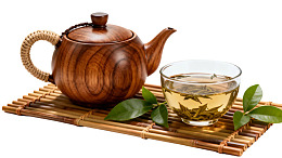 木质茶壶配绿茶置于竹席