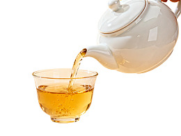 茶壶倾倒金黄色茶水入杯