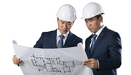 两位戴安全帽的男士查看建筑蓝图